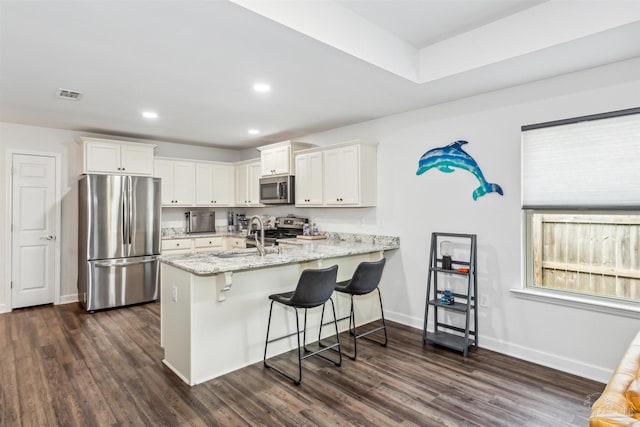 kitchen featuring stainless steel appliances, kitchen peninsula, sink, and white cabinets