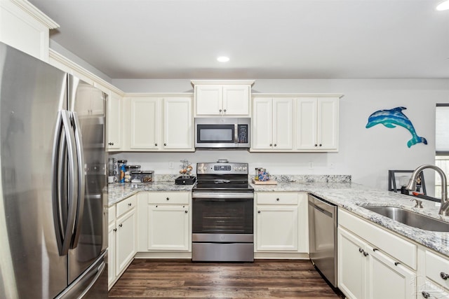 kitchen featuring sink, dark wood-type flooring, appliances with stainless steel finishes, light stone countertops, and kitchen peninsula