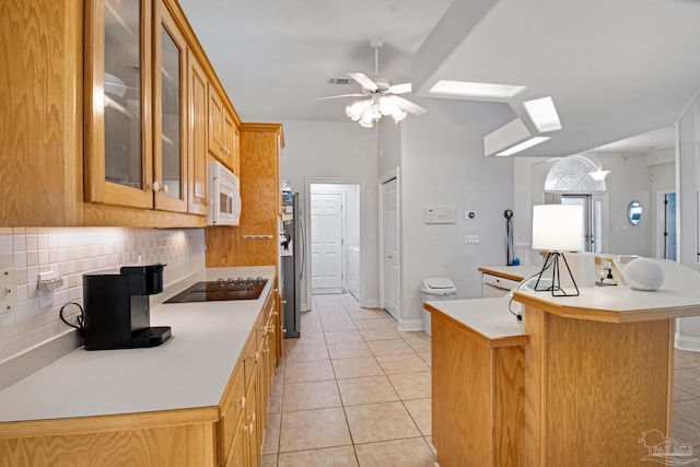 5140 Grumann Dr, Pensacola, FL 32507 - kitchen with white microwave, black electric stovetop, backsplash, light tile patterned floors, and freestanding refrigerator