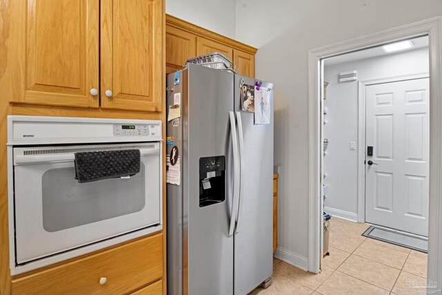 5140 Grumann Dr, Pensacola, FL 32507 - kitchen with stainless steel refrigerator with ice dispenser, light tile patterned flooring, white oven, and baseboards