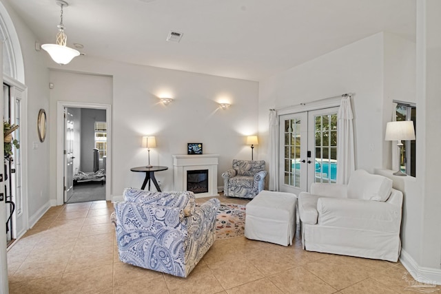 5140 Grumann Dr, Pensacola, FL 32507 - living area with french doors, light tile patterned flooring, a glass covered fireplace, and baseboards