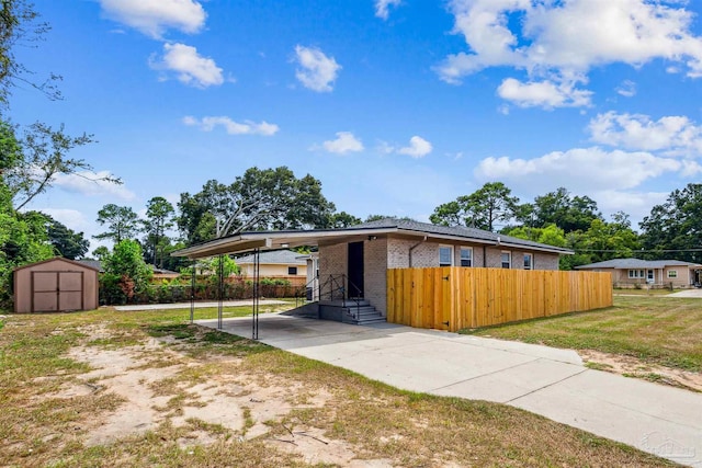 exterior space with a carport, a storage unit, and a front yard