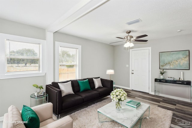 living room featuring a textured ceiling, dark wood-type flooring, beamed ceiling, and ceiling fan