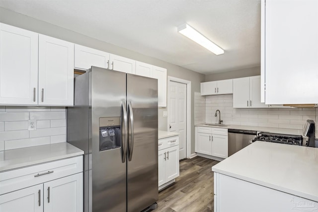 kitchen with sink, appliances with stainless steel finishes, white cabinetry, backsplash, and dark hardwood / wood-style flooring