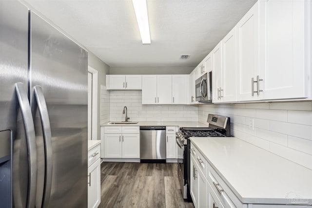 kitchen featuring sink, white cabinetry, stainless steel appliances, tasteful backsplash, and dark hardwood / wood-style flooring