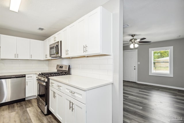 kitchen featuring white cabinetry, appliances with stainless steel finishes, dark wood-type flooring, and backsplash