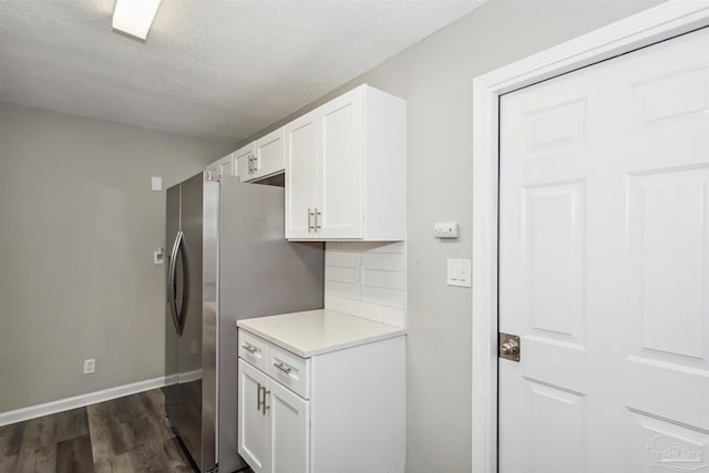 kitchen with white cabinetry, a textured ceiling, stainless steel fridge, dark hardwood / wood-style flooring, and decorative backsplash