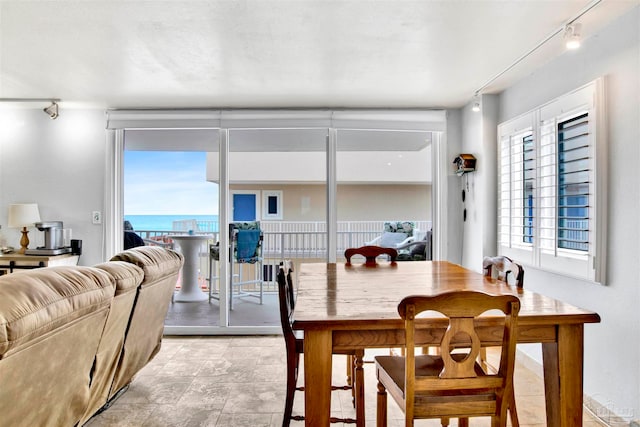 dining area featuring a water view, rail lighting, and a wealth of natural light