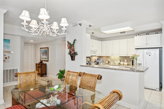 dining area with an inviting chandelier, ornamental molding, and light tile patterned floors