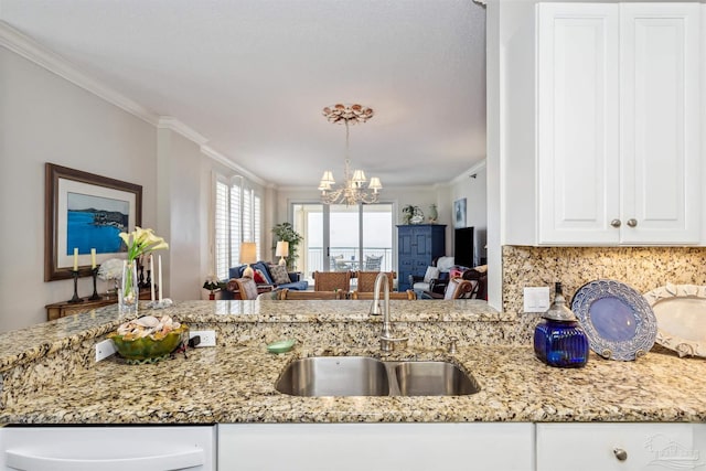 kitchen featuring sink, an inviting chandelier, crown molding, tasteful backsplash, and white cabinets