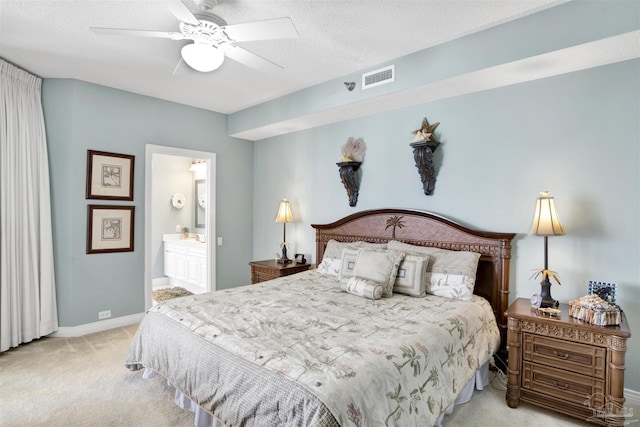 bedroom with ensuite bath, light colored carpet, ceiling fan, and a textured ceiling