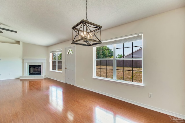 3086 Myrshine Dr, Pensacola, FL 32506 - unfurnished living room with wood finished floors, a textured ceiling, ceiling fan with notable chandelier, a tile fireplace, and baseboards