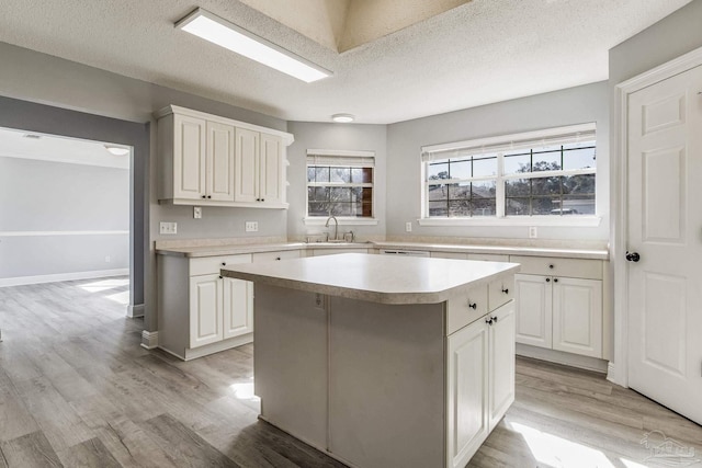 kitchen with sink, white cabinetry, a center island, light hardwood / wood-style floors, and a textured ceiling