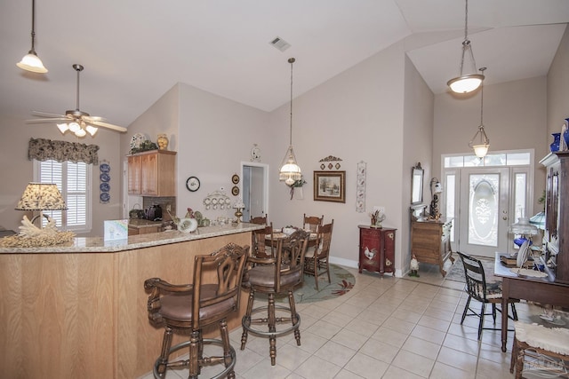 1013 Patriot Pl, Pensacola, FL 32534 - kitchen featuring light tile patterned flooring, high vaulted ceiling, kitchen peninsula, ceiling fan, and light stone countertops