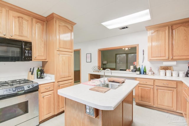 kitchen with gas range, light brown cabinets, a center island with sink, and sink