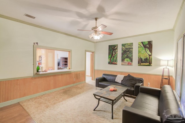 living room with ceiling fan, light hardwood / wood-style floors, wood walls, and ornamental molding