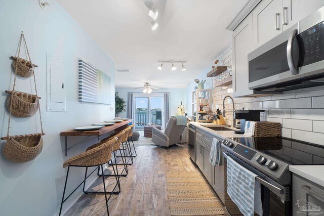 kitchen with ceiling fan, gray cabinetry, light hardwood / wood-style flooring, stainless steel appliances, and decorative backsplash