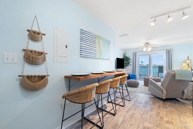 dining space featuring light wood-type flooring, ceiling fan, track lighting, and electric panel