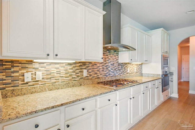2665 Tulip Hill Rd, Pace, FL 32571 - kitchen featuring wall chimney range hood, stainless steel appliances, arched walkways, and white cabinets