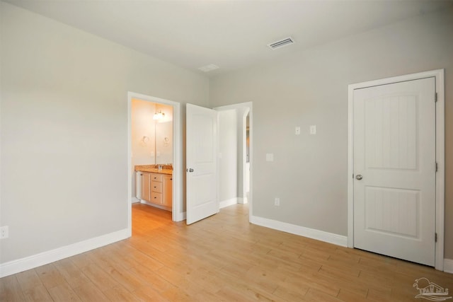 2665 Tulip Hill Rd, Pace, FL 32571 - unfurnished bedroom featuring light wood-style floors, baseboards, and connected bathroom