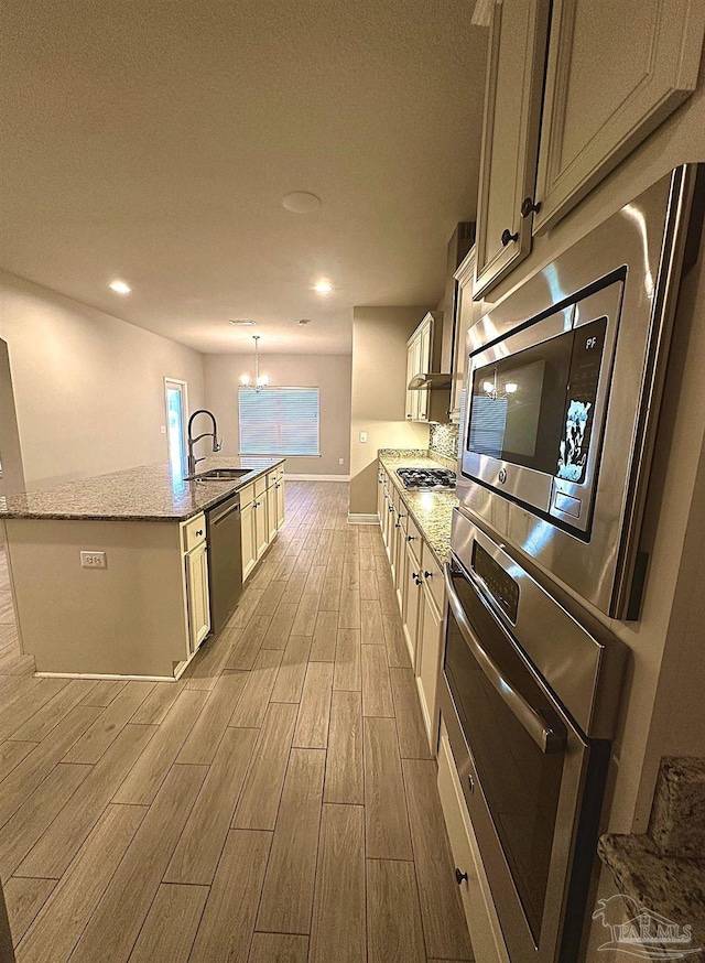 2665 Tulip Hill Rd, Pace, FL 32571 - kitchen featuring appliances with stainless steel finishes, light wood finished floors, a sink, a chandelier, and a kitchen island with sink