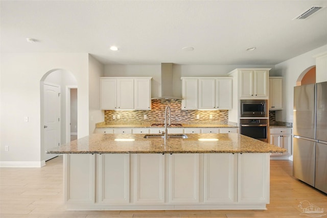 2665 Tulip Hill Rd, Pace, FL 32571 - kitchen with appliances with stainless steel finishes, wall chimney range hood, tasteful backsplash, arched walkways, and light stone countertops