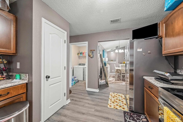 6856 Old W Ln, Milton, FL 32570 - kitchen with brown cabinetry, light wood finished floors, electric range, independent washer and dryer, and baseboards