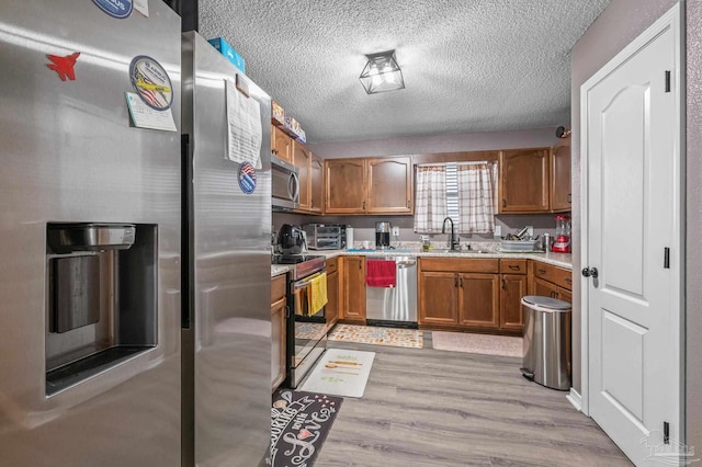 6856 Old W Ln, Milton, FL 32570 - kitchen with stainless steel appliances, light countertops, a sink, brown cabinets, and a textured ceiling
