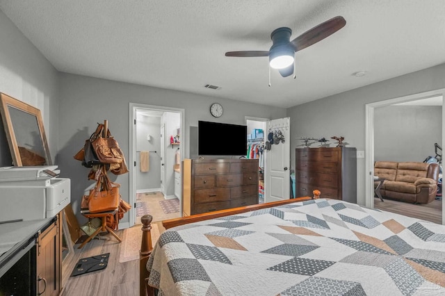6856 Old W Ln, Milton, FL 32570 - bedroom featuring light wood-type flooring, a closet, a textured ceiling, a walk in closet, and connected bathroom