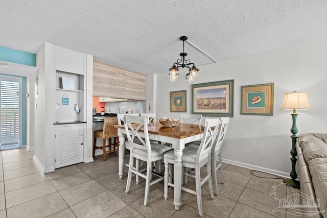 dining area with an inviting chandelier, light tile patterned floors, and a textured ceiling