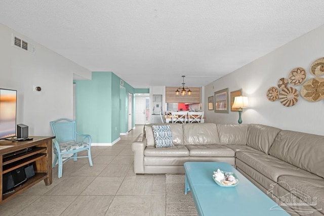 living room featuring an inviting chandelier, a textured ceiling, and light tile patterned floors