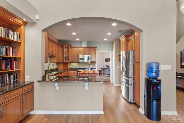 1124 Willowood Cir, Gulf Breeze, FL 32563 - kitchen with stainless steel appliances, arched walkways, a peninsula, and brown cabinetry