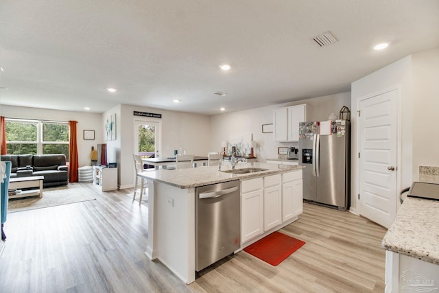 10885 Blacktail Loop, Pensacola, FL 32526 - kitchen featuring appliances with stainless steel finishes, a sink, light wood finished floors, white cabinets, and a kitchen island with sink