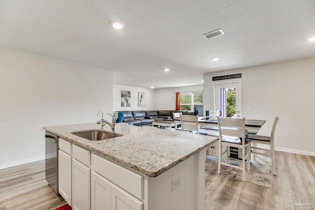 10885 Blacktail Loop, Pensacola, FL 32526 - kitchen featuring a sink, dishwasher, light wood-style flooring, light stone countertops, and a textured ceiling