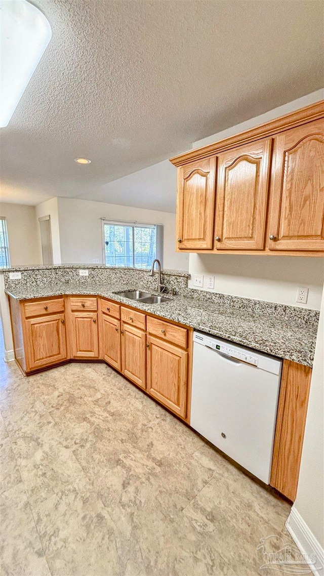 kitchen featuring dishwasher, a textured ceiling, vaulted ceiling, and sink