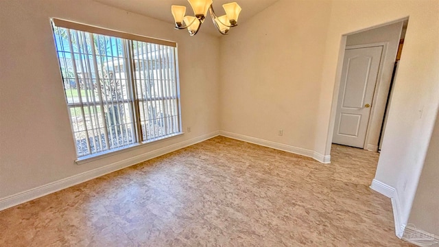 carpeted spare room featuring a chandelier