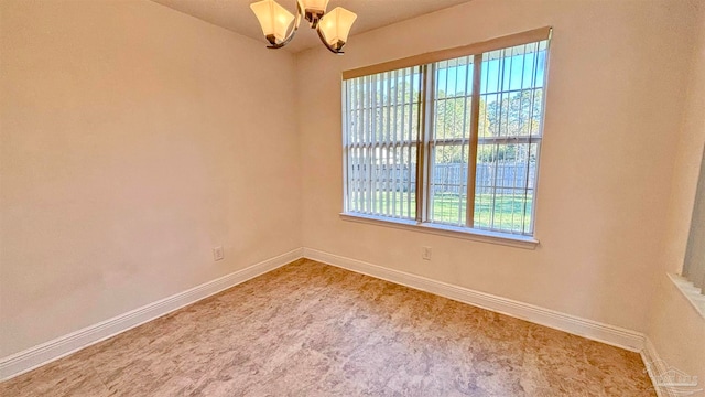 carpeted empty room featuring an inviting chandelier and a healthy amount of sunlight