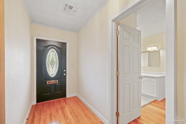 foyer entrance featuring crown molding and light hardwood / wood-style flooring