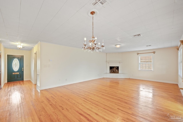 unfurnished living room featuring a notable chandelier and light hardwood / wood-style floors