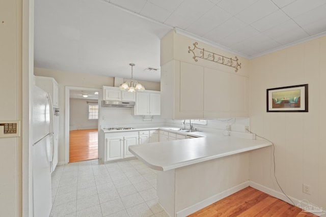 3570 Firestone Blvd, Pensacola, FL 32503 - kitchen with light countertops, a peninsula, under cabinet range hood, a notable chandelier, and freestanding refrigerator