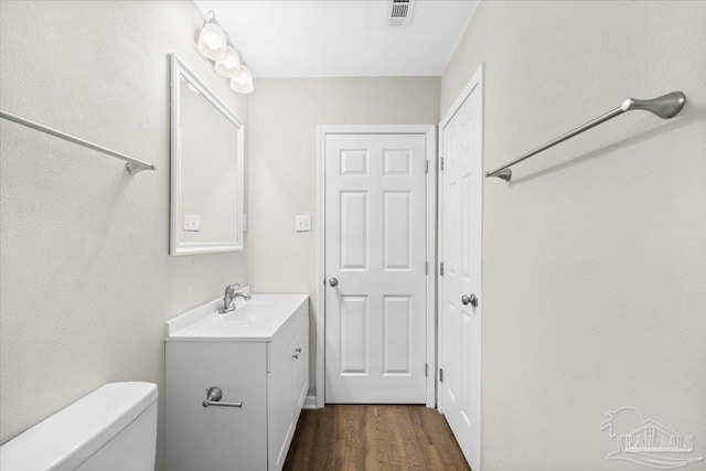 bathroom featuring vanity, wood-type flooring, and toilet