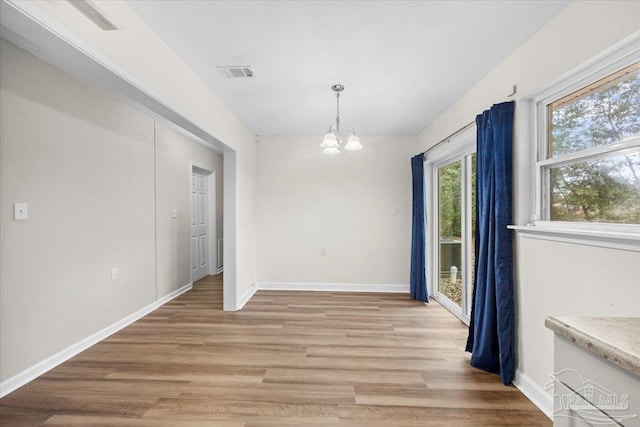 unfurnished dining area featuring light hardwood / wood-style floors and a notable chandelier