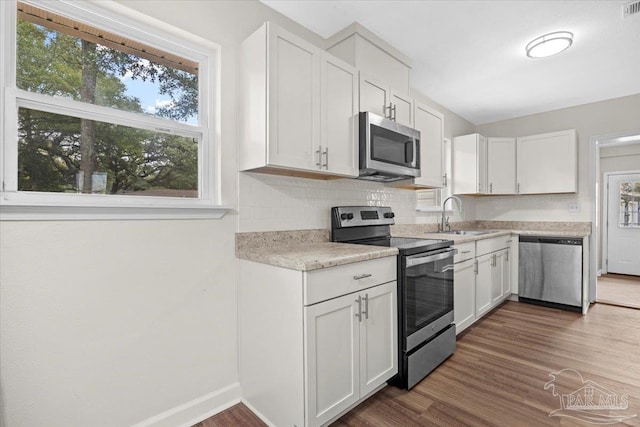 kitchen featuring tasteful backsplash, sink, white cabinets, and appliances with stainless steel finishes