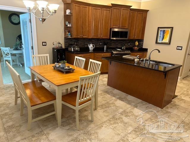 1988 Heritage Park Way, Navarre, FL 32566 - kitchen with appliances with stainless steel finishes, a sink, dark countertops, brown cabinets, and backsplash