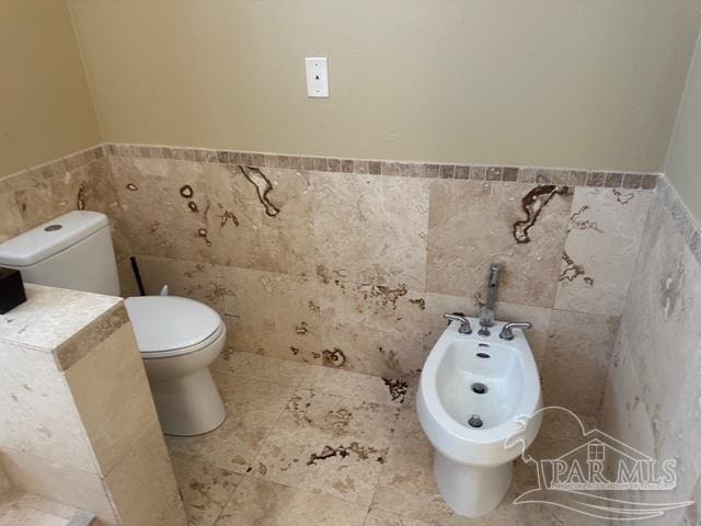 1988 Heritage Park Way, Navarre, FL 32566 - bathroom with tile walls, toilet, a bidet, and a wainscoted wall