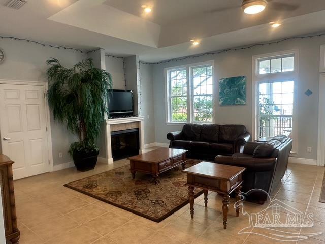 1988 Heritage Park Way, Navarre, FL 32566 - living room with healthy amount of natural light, a tray ceiling, light tile patterned floors, and a fireplace