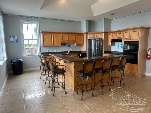 1988 Heritage Park Way, Navarre, FL 32566 - kitchen featuring black appliances, baseboards, a sink, light tile patterned flooring, and a high ceiling