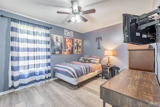 bedroom with ceiling fan, wood finished floors, and a textured ceiling