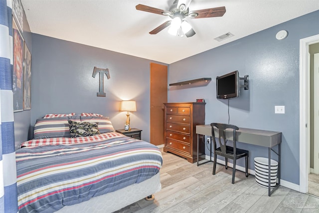 bedroom with wood finished floors, visible vents, a ceiling fan, and baseboards