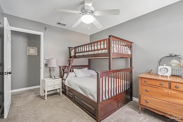 carpeted bedroom with baseboards, a ceiling fan, visible vents, and a textured ceiling